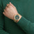 Reloj de hombre en la muñeca con correa de malla dorada y esfera verde oscuro