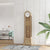 Reloj de pie de madera clara con esfera redonda, frontal de cristal y barras de sonido