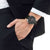 Reloj Citizen para hombre en la muñeca con esfera negra y correa de cuero negra