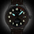 Reloj de hombre con correa de cuero marrón y esfera negra con marcadores luminosos
