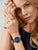 Charm de acero inoxidable en pulsera con incrustación azul, llevado en la muñeca