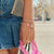 Pulsera con dijes chapados en oro en la muñeca con dijes de corazón y gota y borla rosa