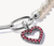 Charm de corazón plateado con gemas moradas, vista lateral en el anillo de unión