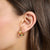 Pendientes de aro de oro amarillo usados con piedras de colores en la oreja