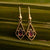 Pendientes dorados con piedra oscura en marco cuadrado de alambre, forma de lágrima.