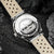 Reloj DS9 de Holzkern con fondo de caja visible, grabado perimetral y correa de cuero gris claro
