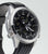 Reloj de hombre en caja plateada con correa negra y esfera negra de perfil