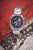 Reloj Casio Edifice para hombre en ángulo: correa de acero inoxidable plateada, esfera negra y detalles en rojo