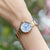 "Reloj de mujer en la muñeca con pulsera dorada y esfera azul"