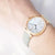 Reloj de mujer en la muñeca: caja en tono oro rosa, esfera plateada, correa de piel beige.