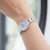 Reloj de mujer en la muñeca con esfera azul y pulsera de metal plateado con detalles en oro rosa