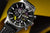 Reloj de hombre en diagonal: esfera negra, caja plateada, correa de cuero negra