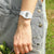 "Reloj digital para mujer con pulsera blanca en la muñeca, pantalla visible sobre mezclilla"
