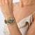 Reloj de mujer en la muñeca con esfera verde y pulsera de acero inoxidable dorado y plateado