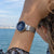 "Reloj de mujer en la muñeca con esfera azul y correa milanesa de metal plateado"