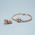 Charm de acero inoxidable en tono oro rosa en pulsera trenzada con detalles de corazón
