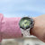 Reloj de hombre de acero inoxidable en la muñeca con esfera verde y bisel negro