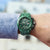 Cronógrafo deportivo para hombre en la muñeca: esfera verde y brazalete de metal verde.