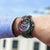 Reloj de hombre en la muñeca: pulsera de metal negro, esfera de cronógrafo multicolor
