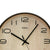 Runde Wanduhr mit beigem Zifferblatt, schwarzen Ziffern und Zeigern.