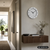 Beige Wanduhr an der Wand mit weißem Rand, schwarzen Zeigern und Ziffern