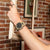Reloj Casio G-Shock para hombre en la muñeca con correa beige, caja visible en vista lateral