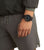Reloj de hombre con correa negra en la muñeca, esfera negra con marcadores azules