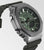 Reloj de hombre en diagonal desde el frente: caja de metal, esfera verde con pantalla, correa negra.