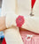 Reloj rojo de mujer en la muñeca con esfera redonda y correa de silicona.