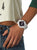 Reloj de mujer en la muñeca: pulsera de plástico blanco, esfera negra