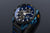 Vista lateral de reloj para hombre: esfera azul, caja negra, correa perforada azul
