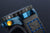 Carcasa con corona/botón dorado y acento azul, correa negra con costura azul