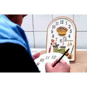 Reloj de pared pintado a mano con diseño de tetera, números redondos y manecillas doradas.
