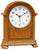 Reloj de mesa de madera con caja abombada y esfera blanca, manecillas negras.
