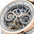 Primer plano de reloj de hombre: esfera esqueletizada con fase lunar, detalles en azul oscuro y líneas en color oro rosa.