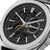 Reloj de hombre primer plano: esfera negra esqueletizada con detalles dorados, caja plateada