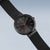 Vista lateral de un reloj de pulsera Bering: esfera negra con acento central rojo y correa negra
