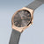 Reloj de mujer en primer plano: bisel de oro rosa, esfera gris oscuro, correa milanesa