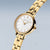 "Reloj de mujer con esfera redonda en blanco y brazalete de eslabones en tono dorado, vista lateral."