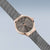 Vista lateral de reloj para mujer: bisel de oro rosa, esfera gris oscuro y correa de malla milanesa