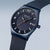 Reloj de hombre con esfera azul, detalles naranjas y correa de malla metálica