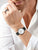 Reloj Bering Ultra Slim en la muñeca con correa de cuero negra y esfera redonda blanca