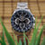 Reloj plateado para hombre con esfera azul y correa de metal, botones visibles