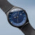 Reloj de hombre, vista inclinada: esfera azul, bisel negro y correa de malla negra
