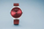 Reloj Bering redondo con esfera roja iridiscente y caja plateada, correa de malla
