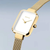 Reloj de mujer con caja rectangular, esfera blanca y correa milanesa dorada.