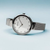 Reloj de mujer en vista lateral con pulsera milanesa plateada y esfera redonda