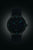 "Reloj de mujer con correa oscura y esfera oscura, marcadores luminosos azules"