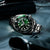 Reloj de pulsera para hombre visible de lado con esfera verde, bisel negro, acero inoxidable