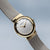 Reloj de mujer con correa milanesa plateada, bisel dorado y esfera blanca